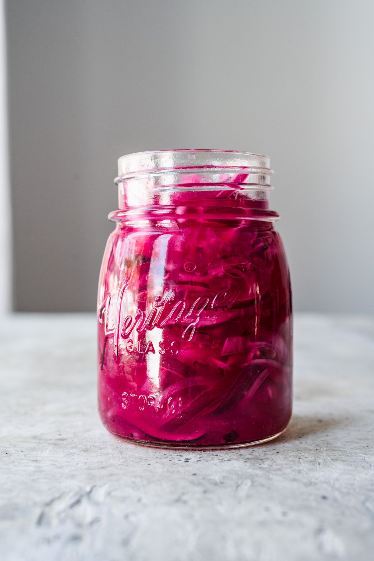 Front view of pickled red onions in a jar.