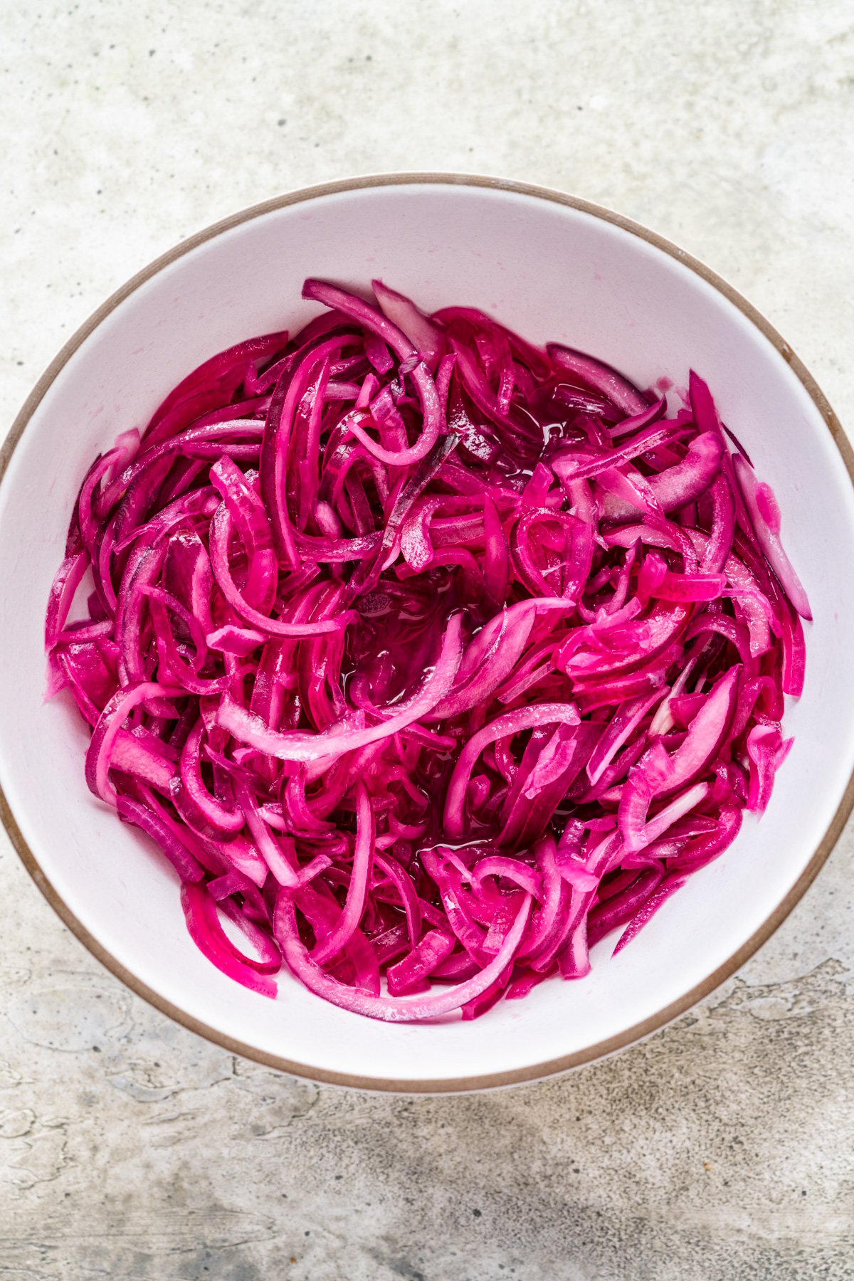 Overhead view of pickled red onions in a bowl.