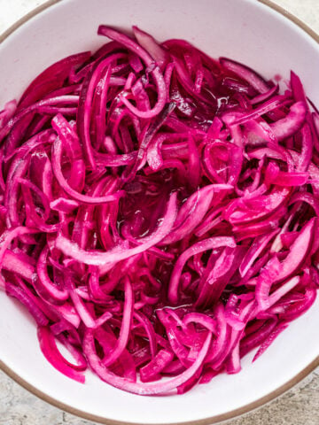 Overhead view of pickled red onions in a bowl.
