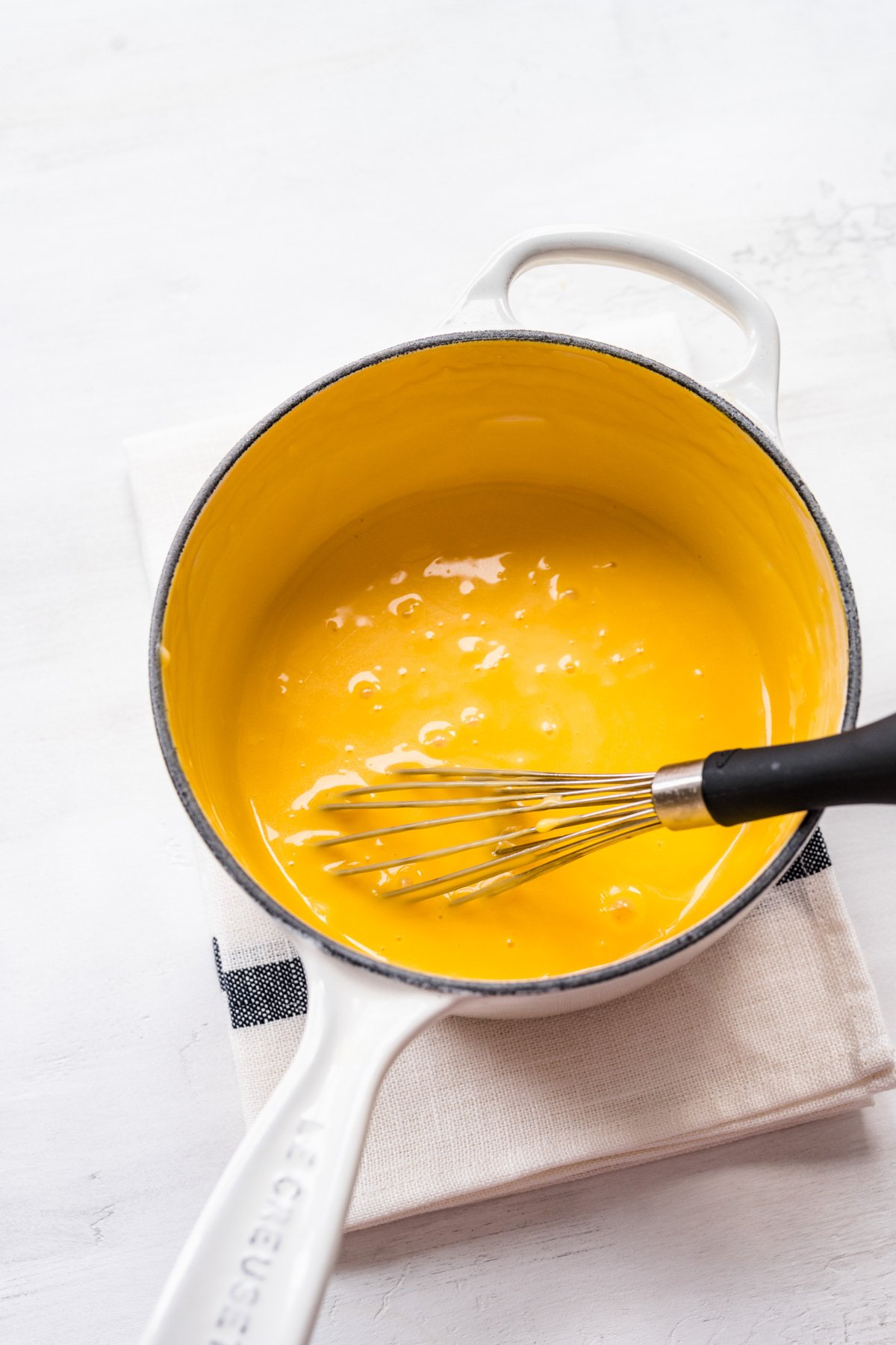 Overhead view of cheese sauce in a saucepan.