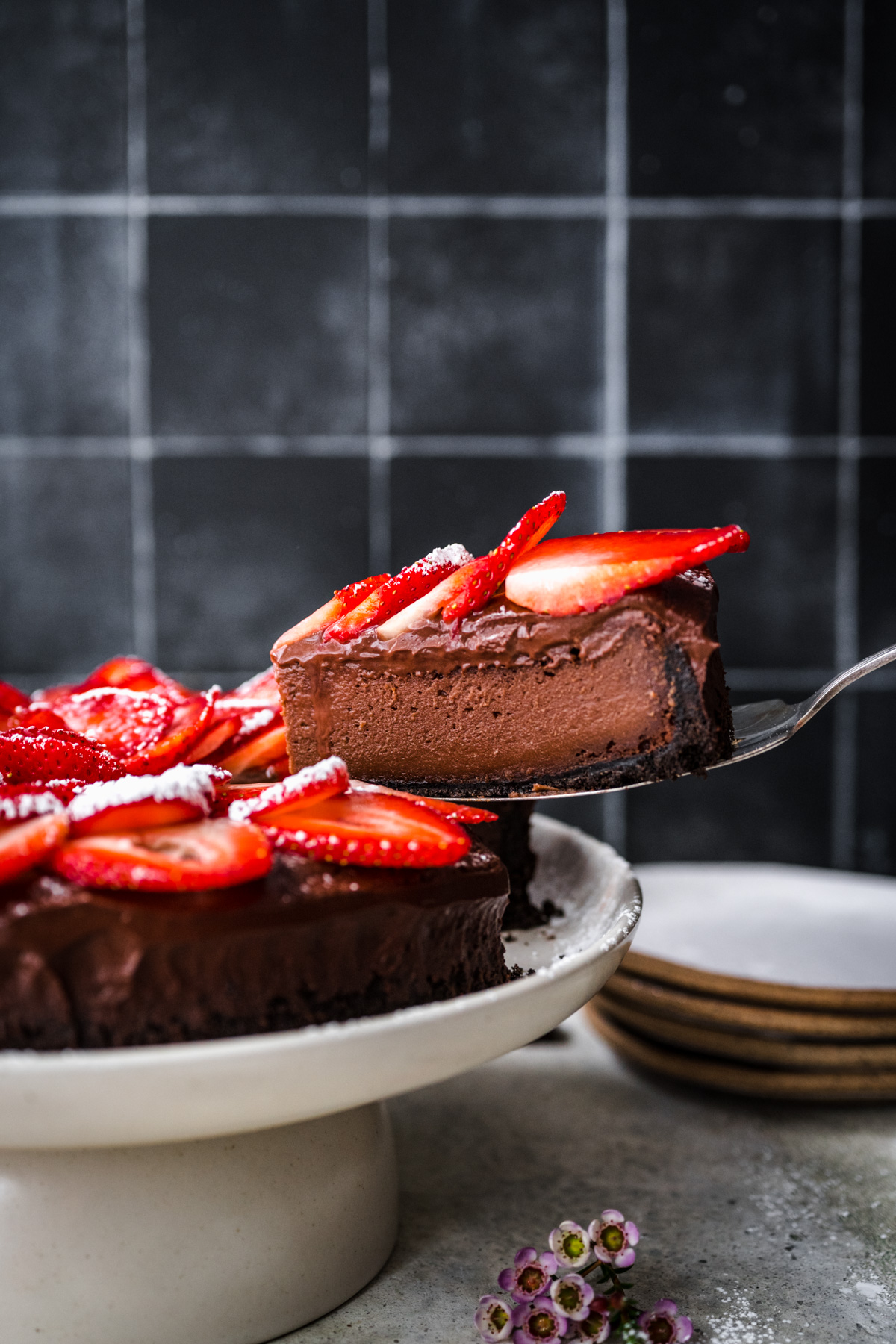 person holding slice of vegan chocolate cheesecake. 