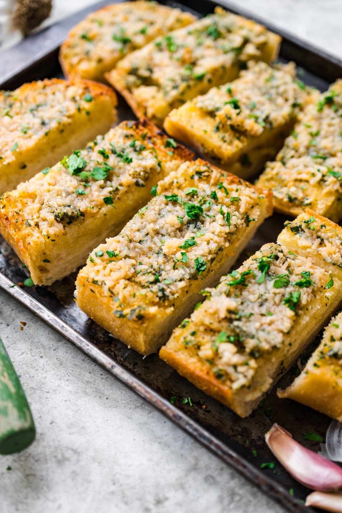 Overhead view of vegan garlic bread with vegan cheese and a garnish of herbs.