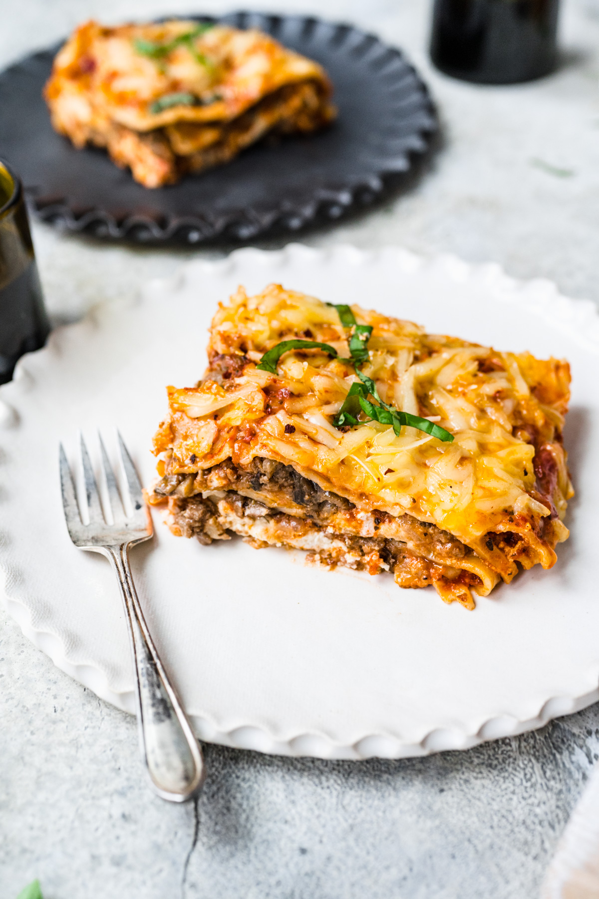 Front view of vegan lasagna on a plate with a fork next to it.