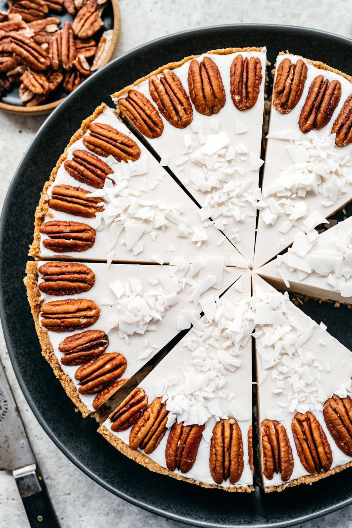 Overhead view of white chocolate cheesecake on a black tray.