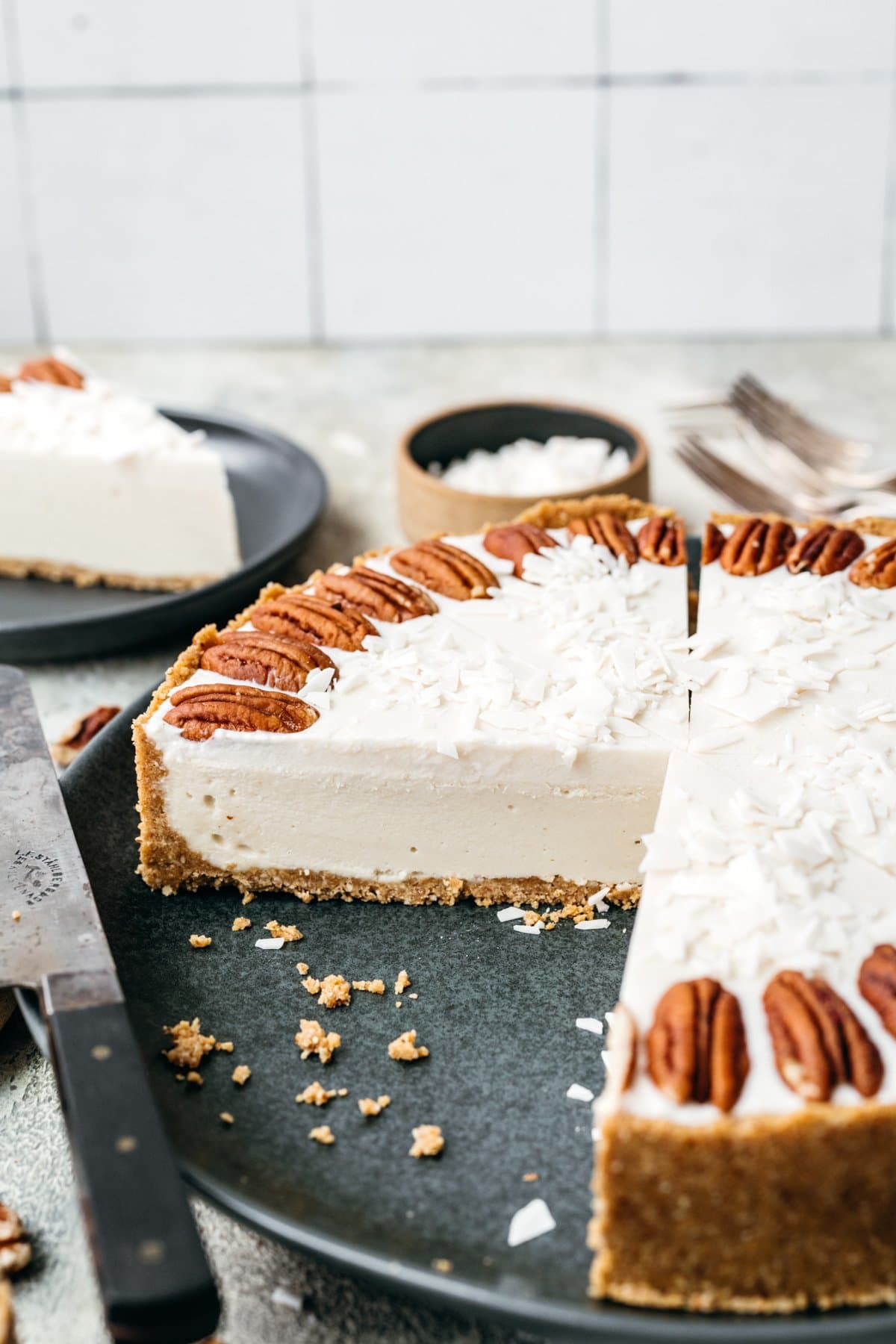 Side view of a slice of no bake white chocolate cheesecake on a black plate.