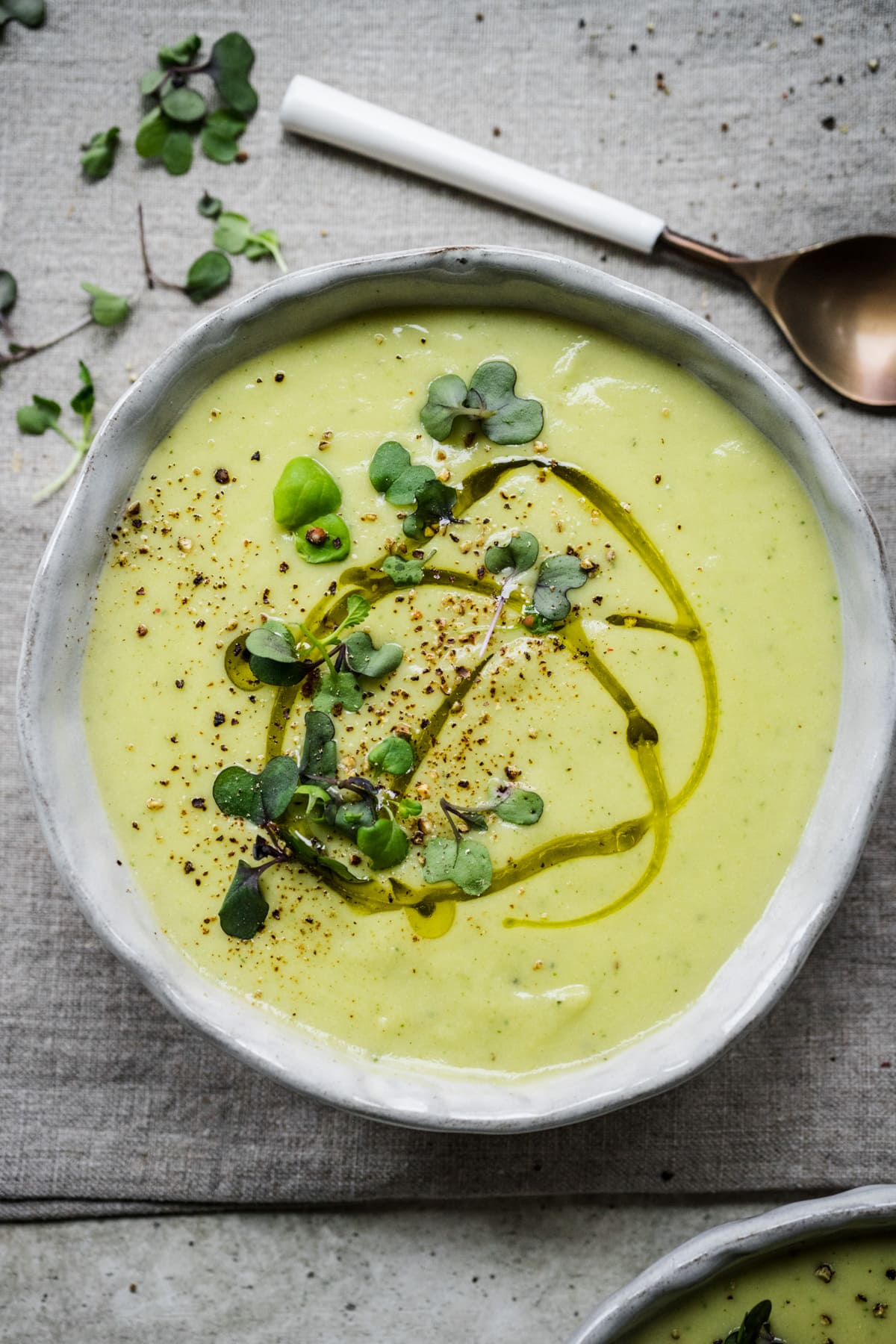 Overhead view of cauliflower leek soup in a bowl garnished with herbs.