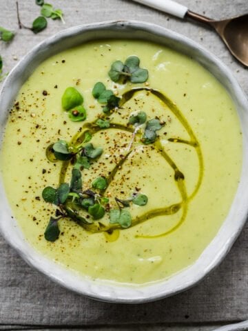 Overhead view of cauliflower leek soup garnished with herbs.