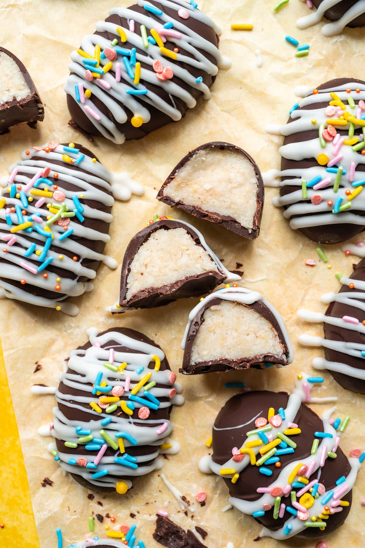 Chocolate coconut easter eggs with white chocolate and sprinkles on yellow backdrop.