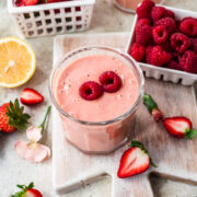 Overhead view of strawberry banana mango smoothie with a raspberry on top.