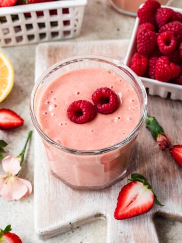 Overhead view of strawberry banana mango smoothie with a raspberry on top.