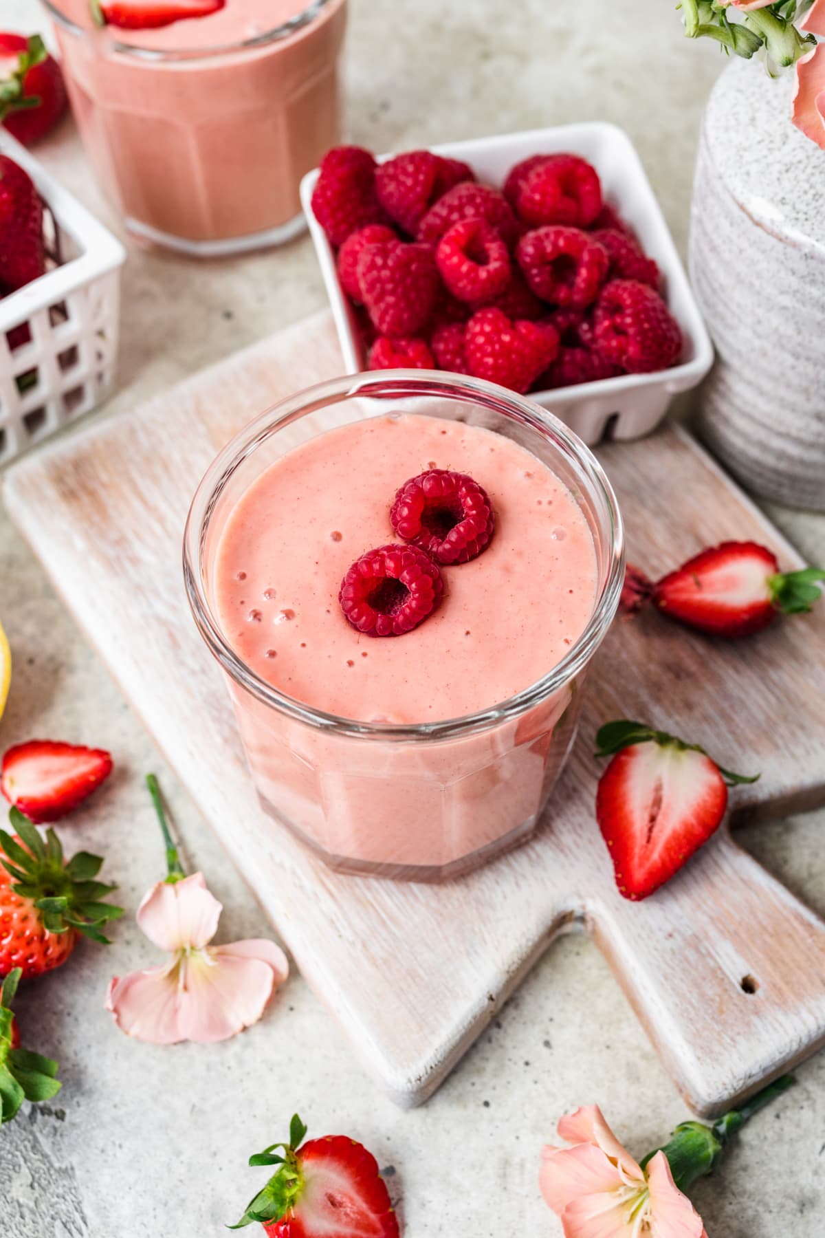 Overhead view of mango strawberry banana smoothie with raspberries on top.