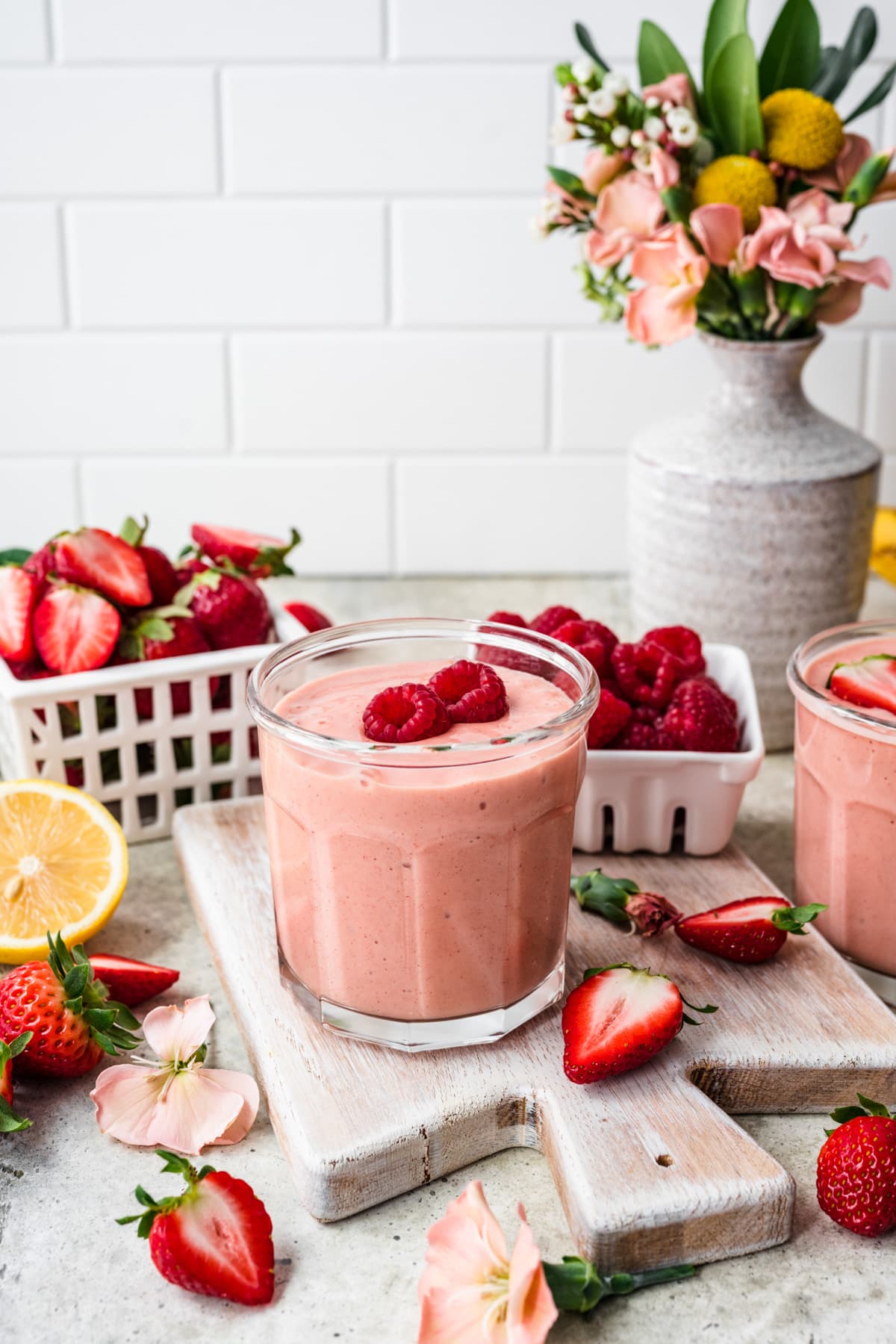 Side view of mango strawberry banana smoothie with raspberries on top.