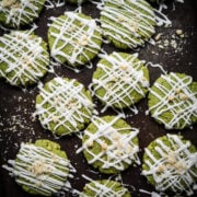 Overhead view of vegan matcha cookies with white chocolate drizzle on baking sheet.