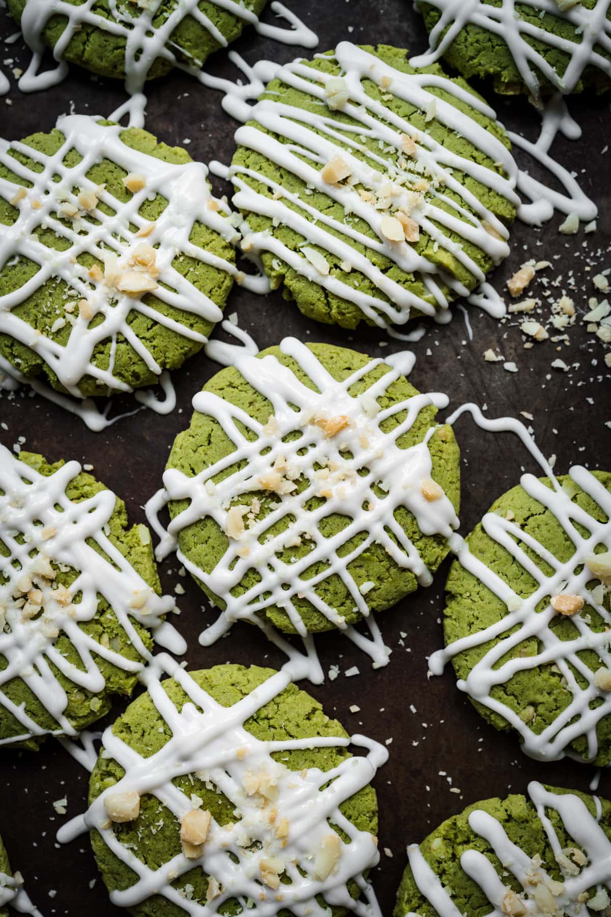 Overhead view of vegan matcha cookies with white chocolate drizzle on baking sheet. 