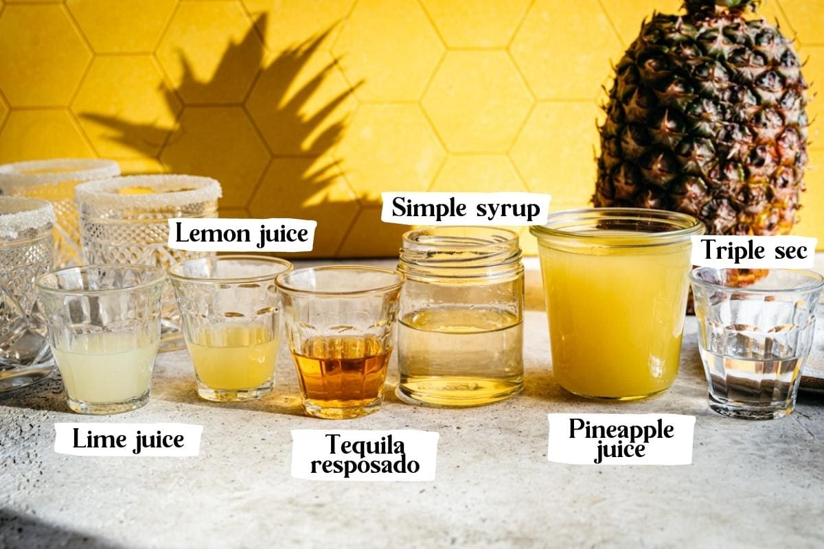 Side view of ingredients for pineapple margarita in small jars. 