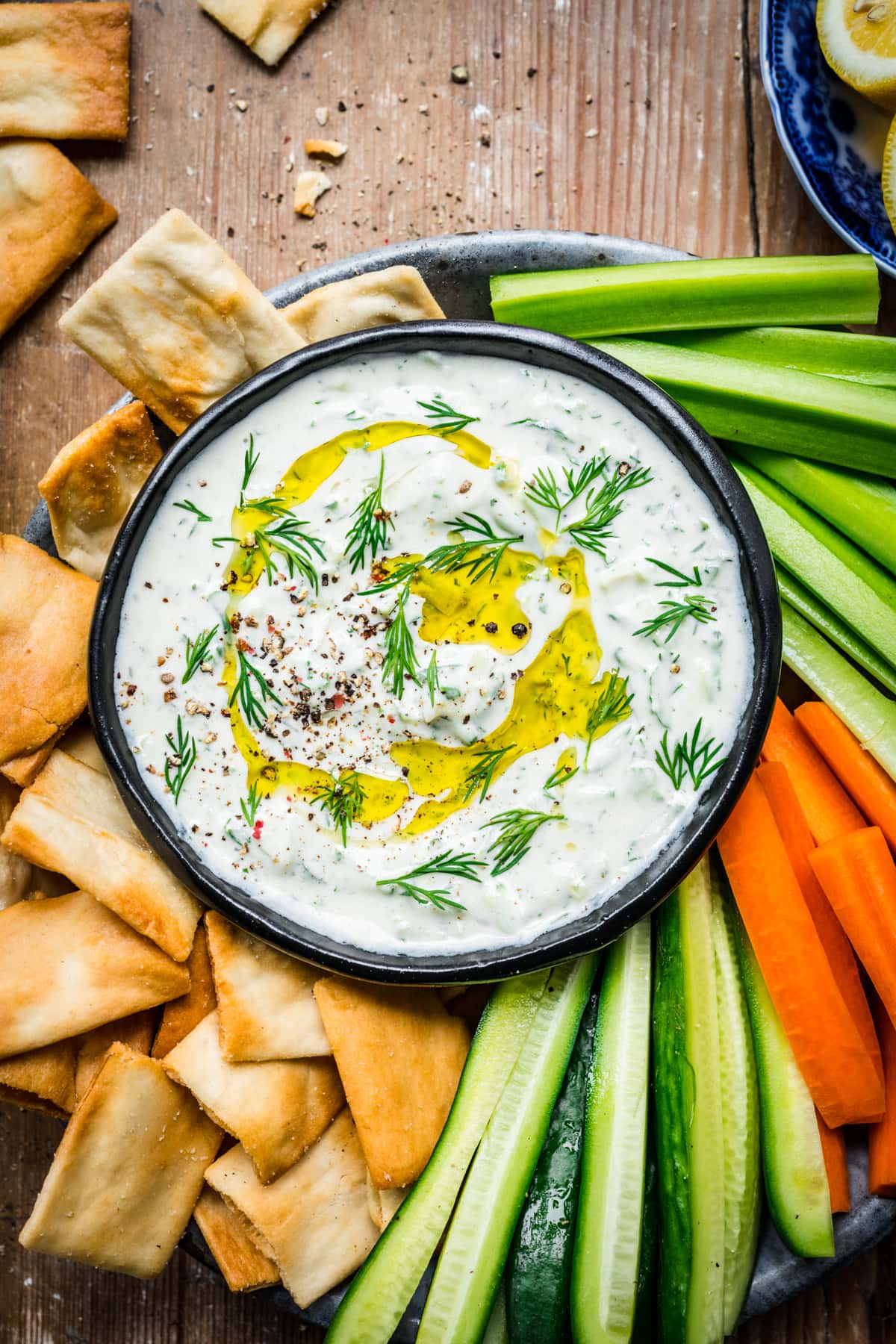 Vegan tzatziki in a bowl surrounded by veggies and chips.