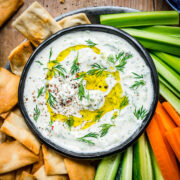 Vegan tzatziki in a bowl surrounded by veggies and chips.