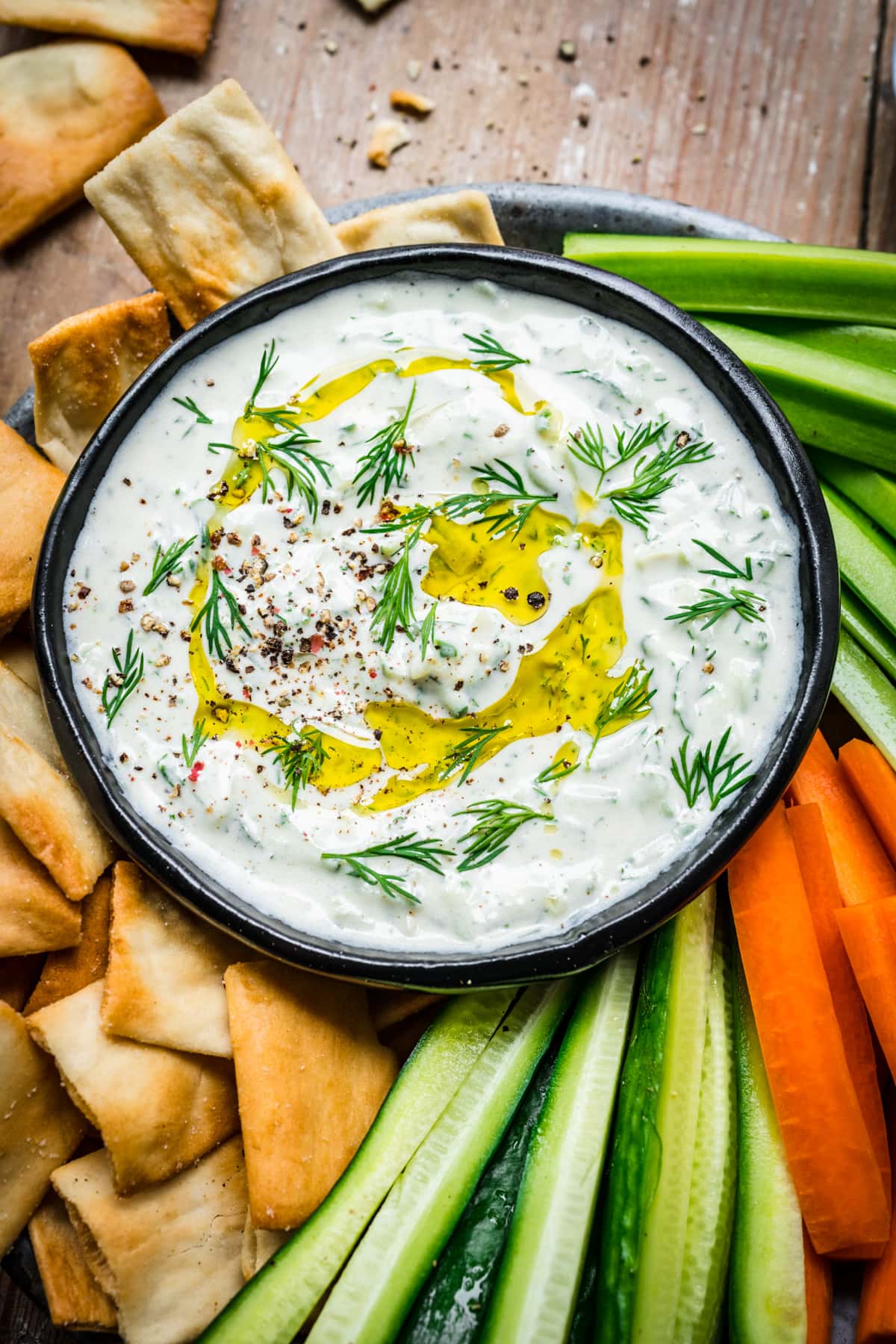 Vegan tzatziki in a bowl surrounded by veggies and chips.