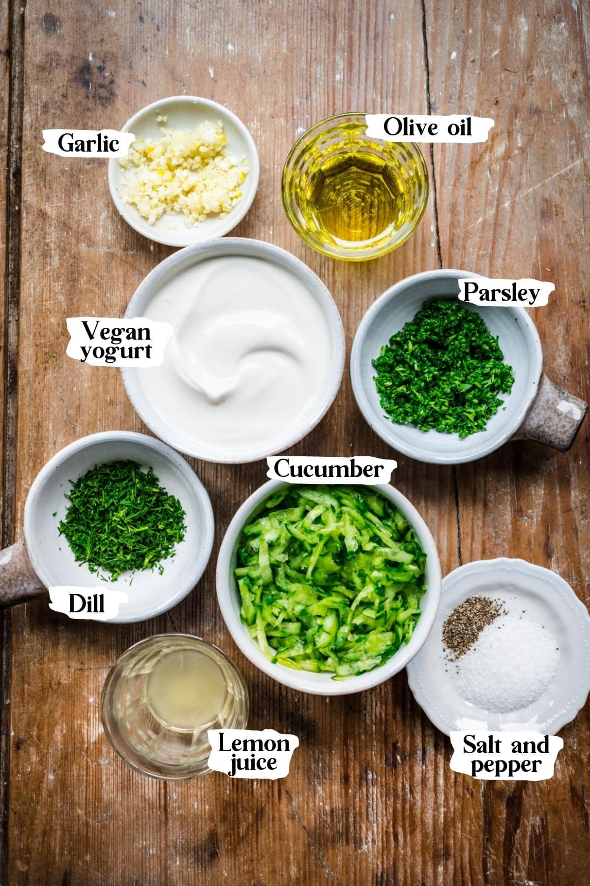 Overhead view of ingredients for vegan tzatziki in small prep bowls. 