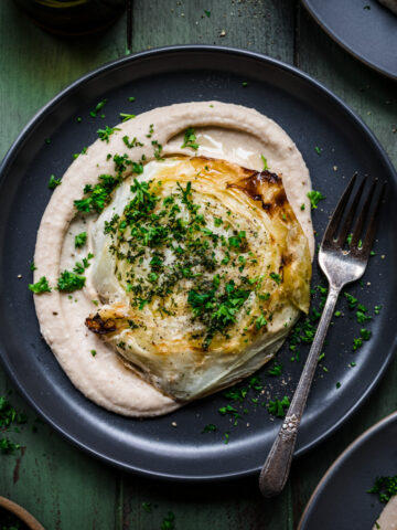 Overhead view of cabbage steaks on a plate atop white bean puree.