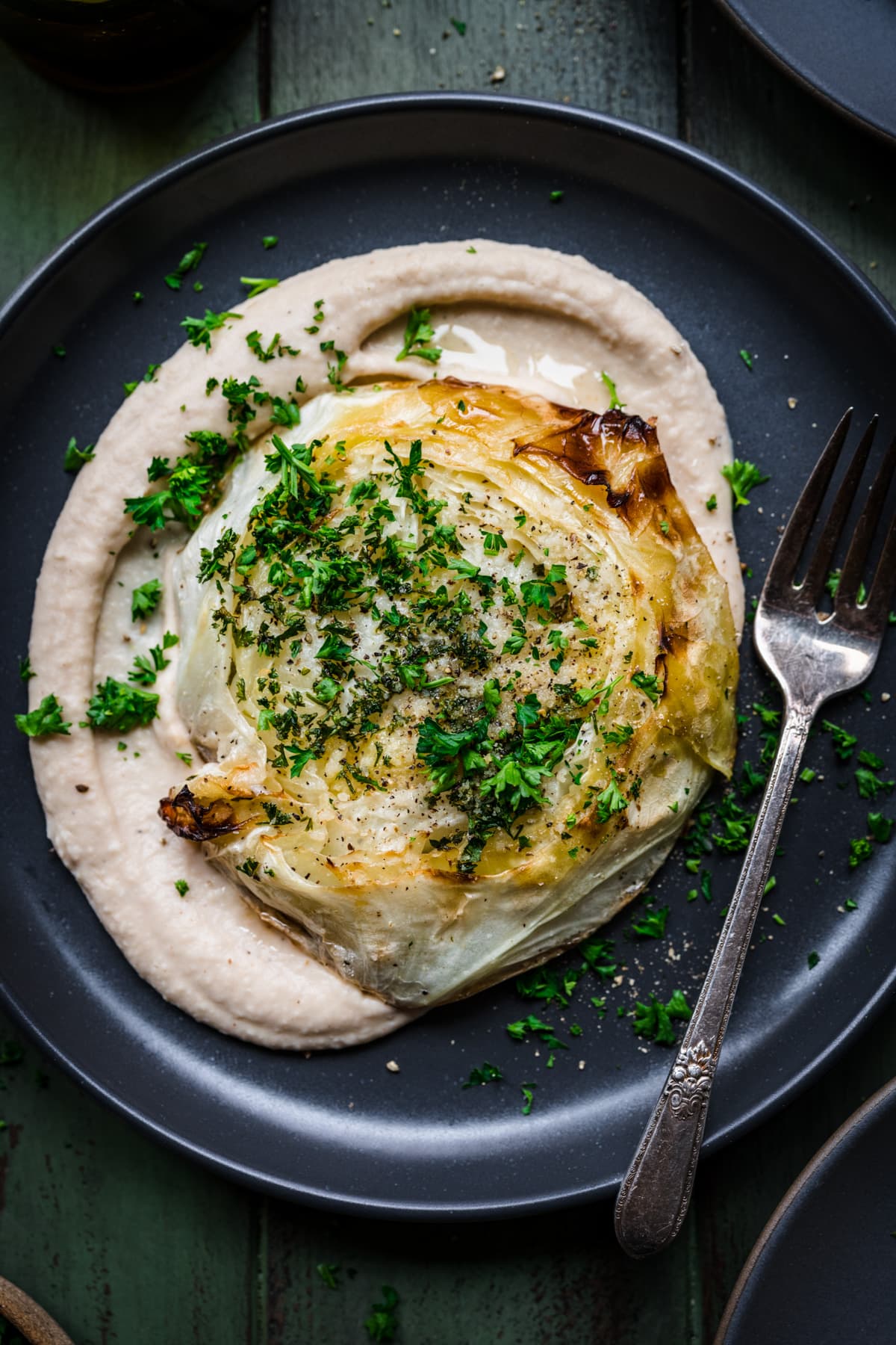 Overhead view of roasted cabbage steak on a plate with bean puree.