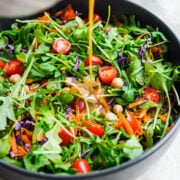 Front view of creamy balsamic dressing being poured over salad.