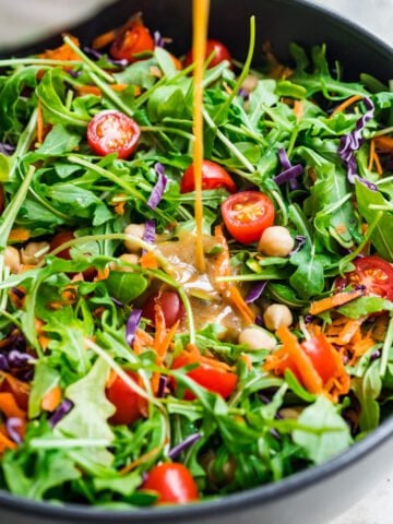 Front view of creamy balsamic dressing being poured over salad.