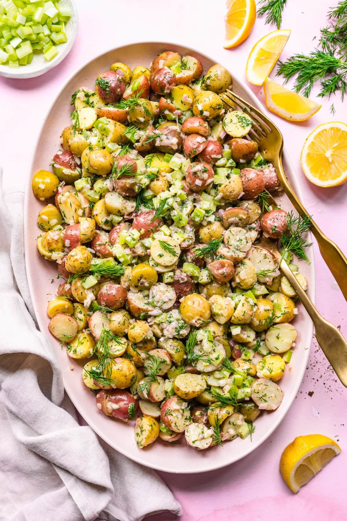 Overhead view of dill potato salad on pink serving platter. 