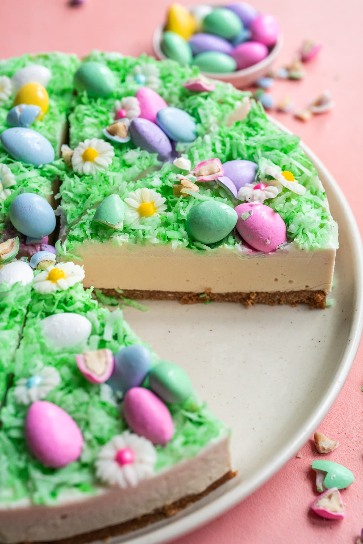 close up side view of slice of no bake easter egg cheesecake on white plate. 