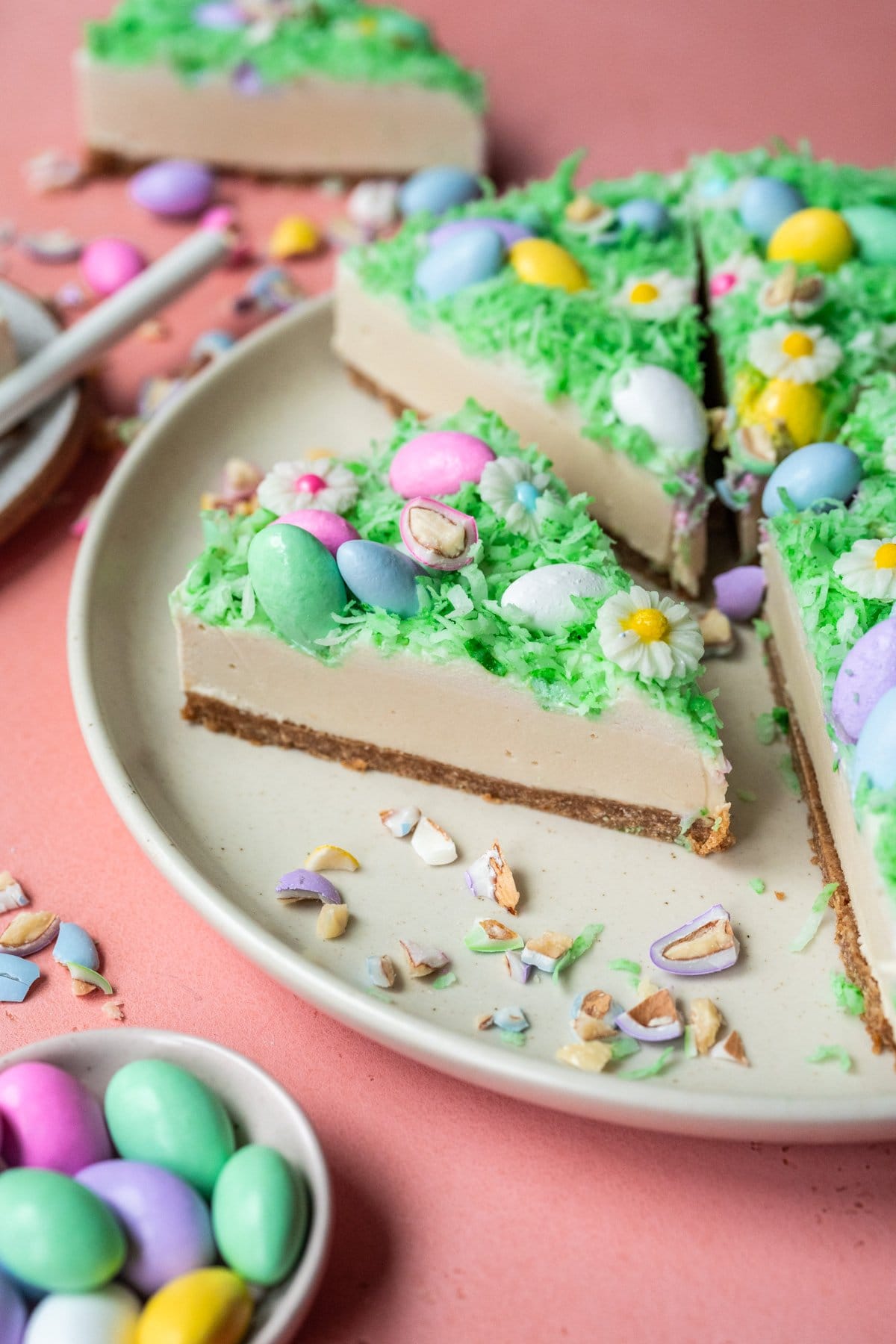 close up side view of slice of no bake easter egg cheesecake on white plate. 