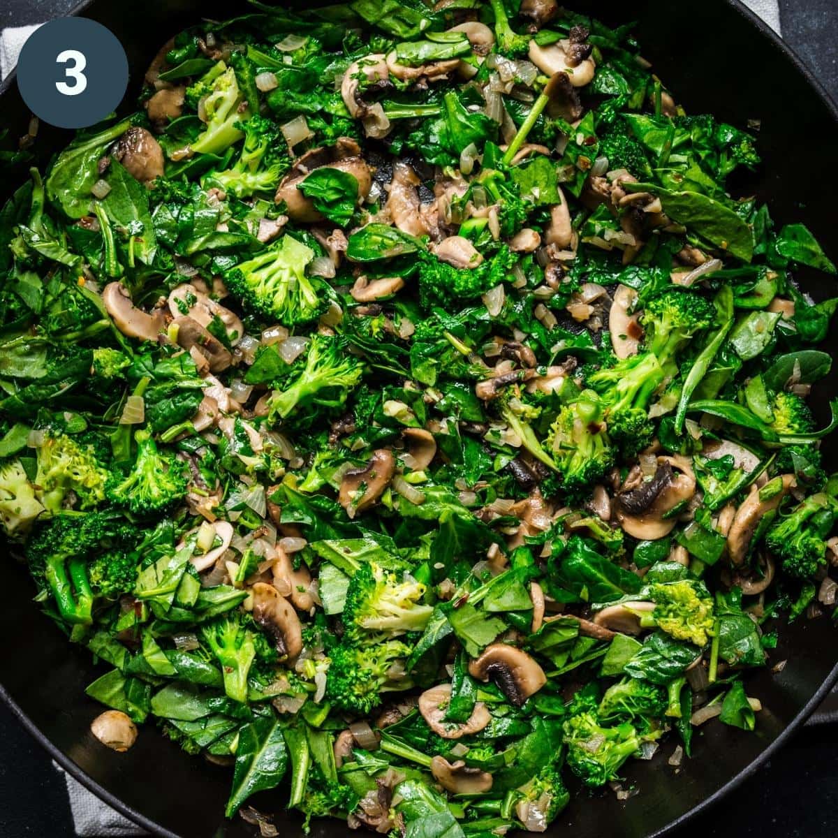 Sautéed mushrooms, spinach and broccoli in pan. 