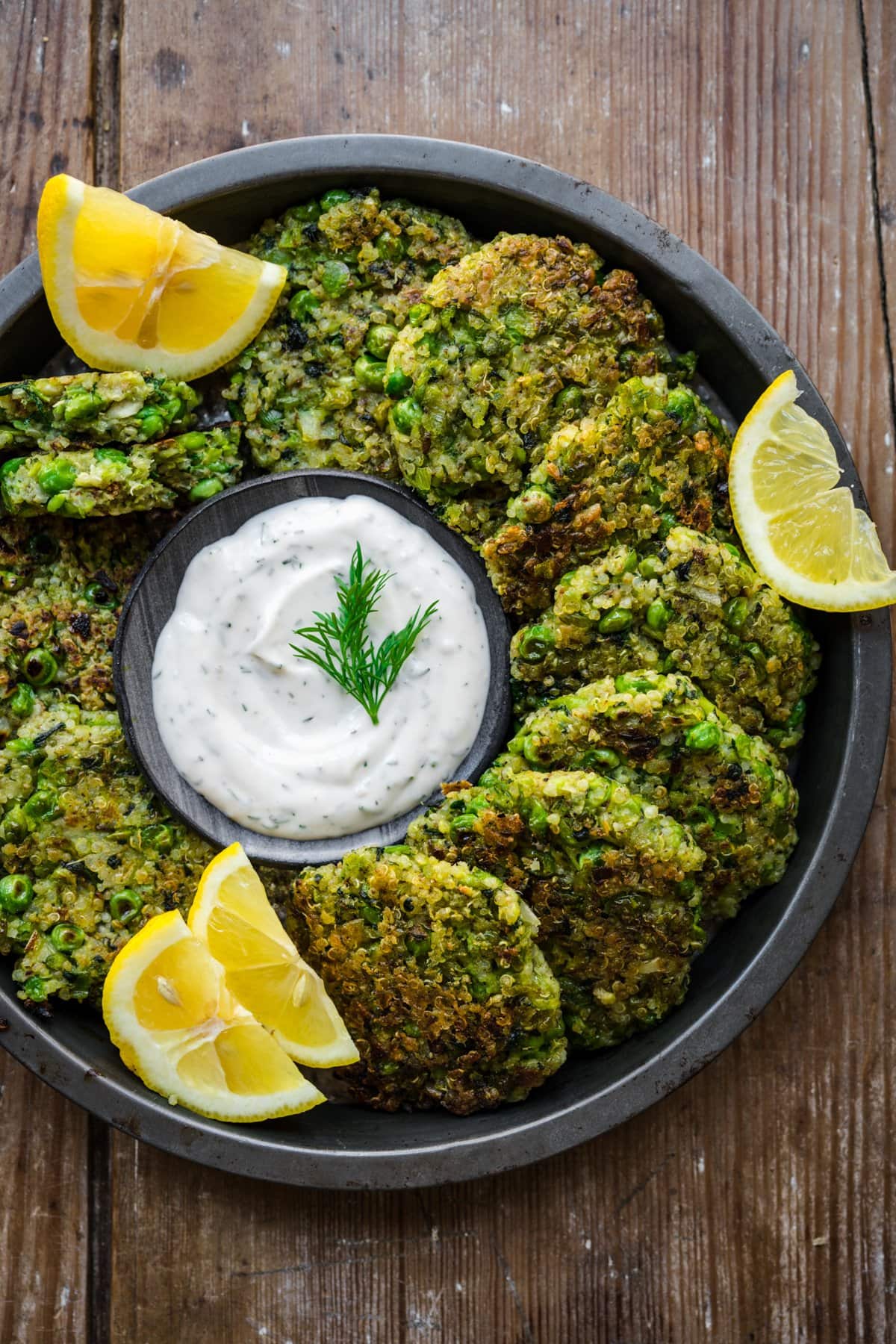 Pea fritters arranged in a circle around lemon dill sauce.