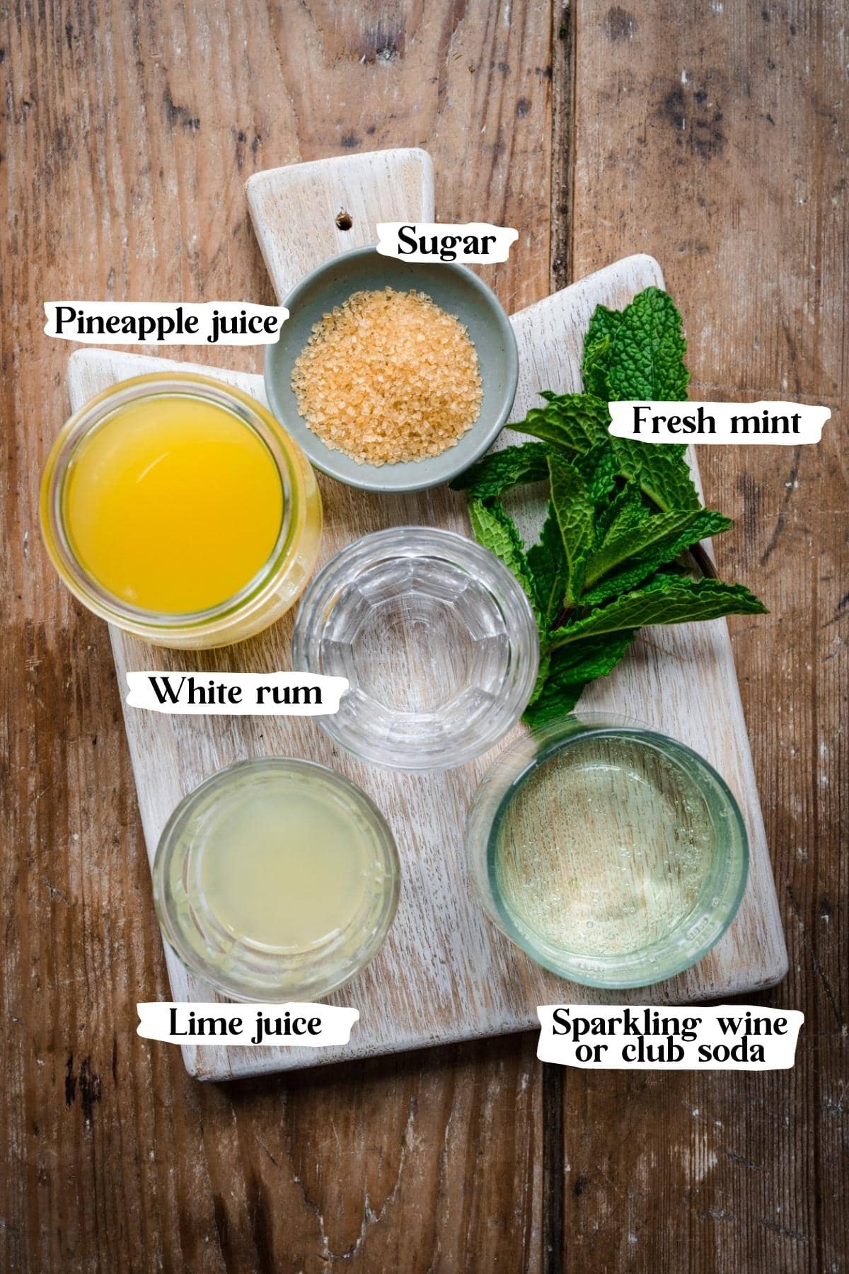 Overhead view of ingredients for pineapple mojito in small jars with text labels. 