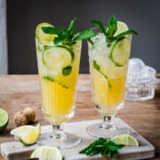 Side view of 2 pineapple mojito cocktails in highball glasses with mint garnish.