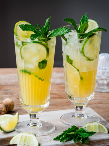 Side view of 2 pineapple mojito cocktails in highball glasses with mint garnish.