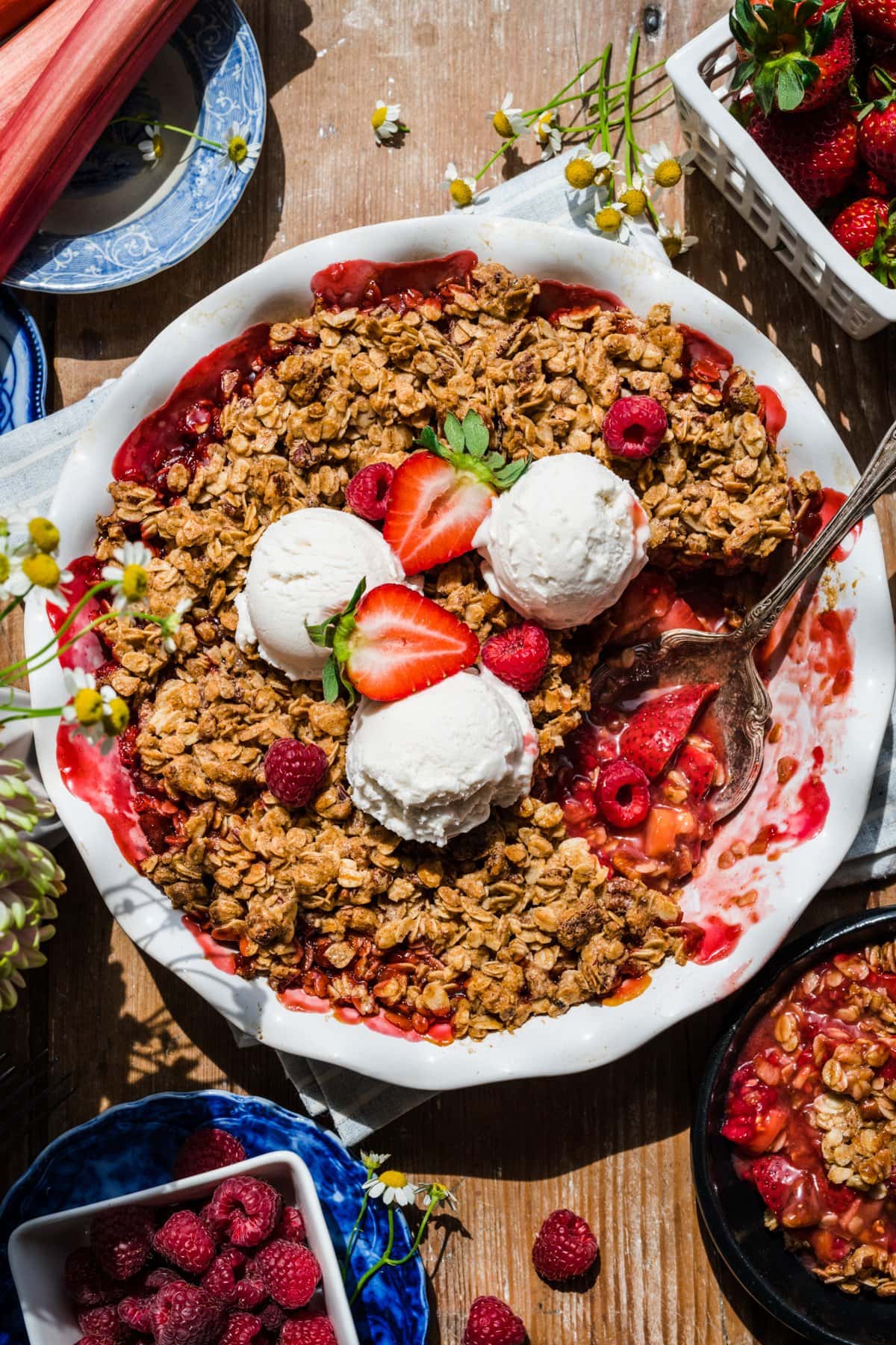 overhead view of vegan and gluten free strawberry rhubarb crisp with vanilla ice cream. 