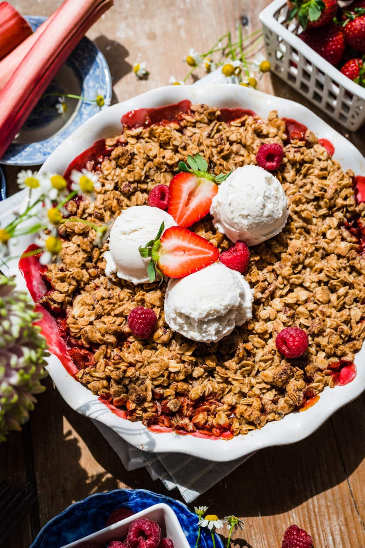 overhead view of vegan and gluten free strawberry rhubarb crisp with vanilla ice cream. 