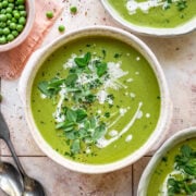 Overhead view of broccoli and pea soup with a cream and herb garnish.