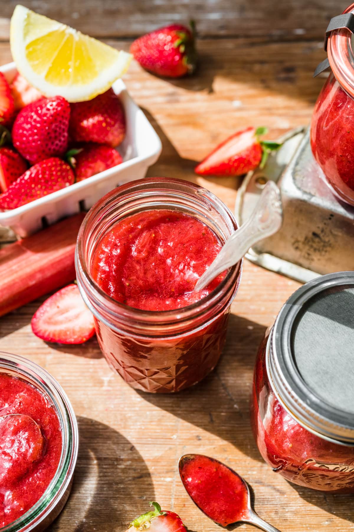 Overhead view of strawberry rhubarb jam in a mason jar with a spoon sticking out.