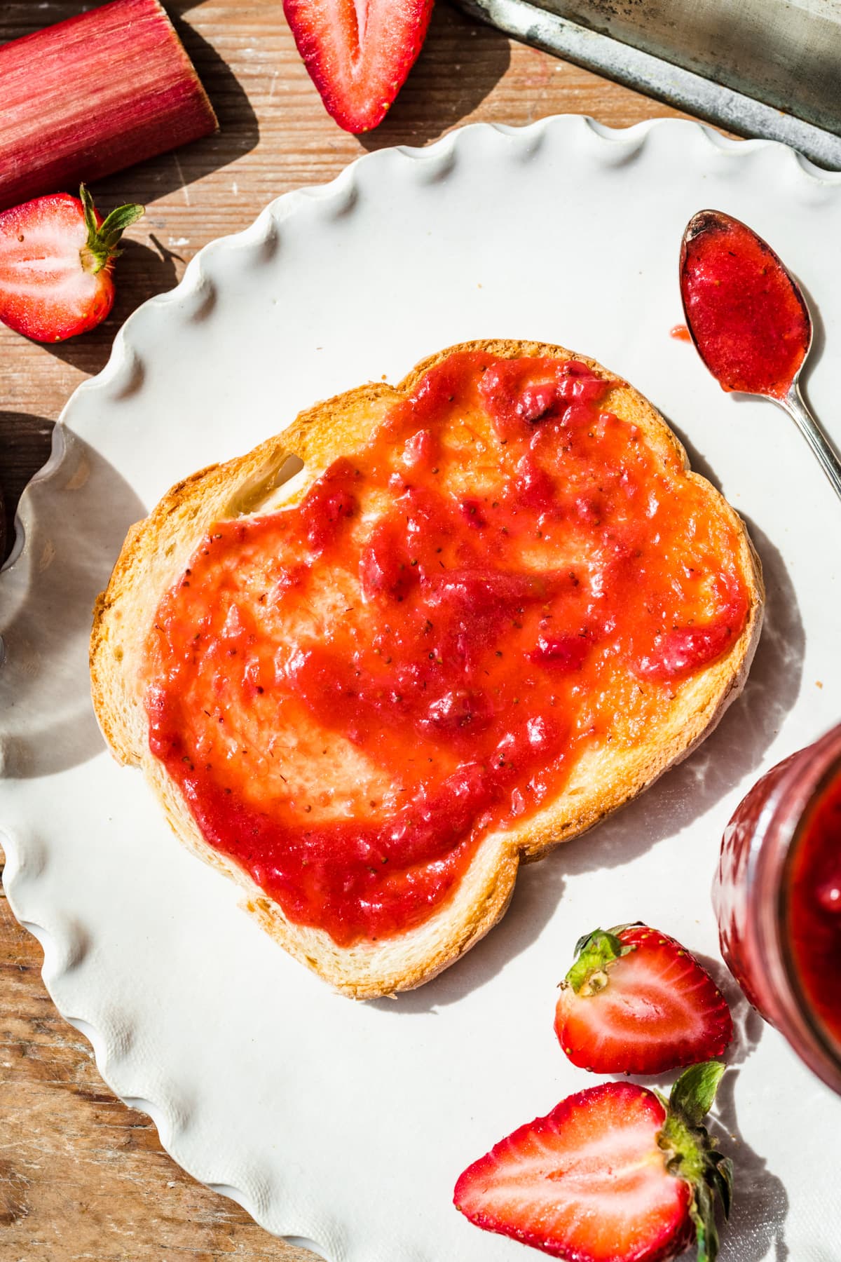 Overhead view of strawberry rhubarb jam spread onto toast.