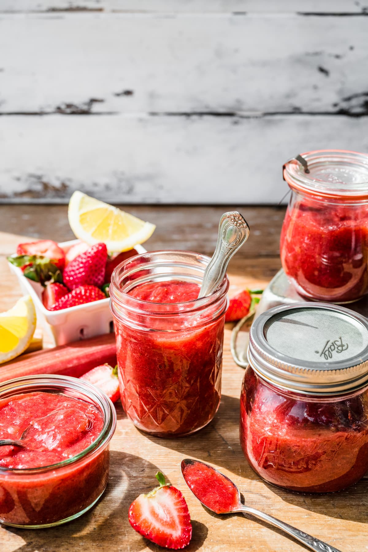 Several jars of jam on top of a wooden table.