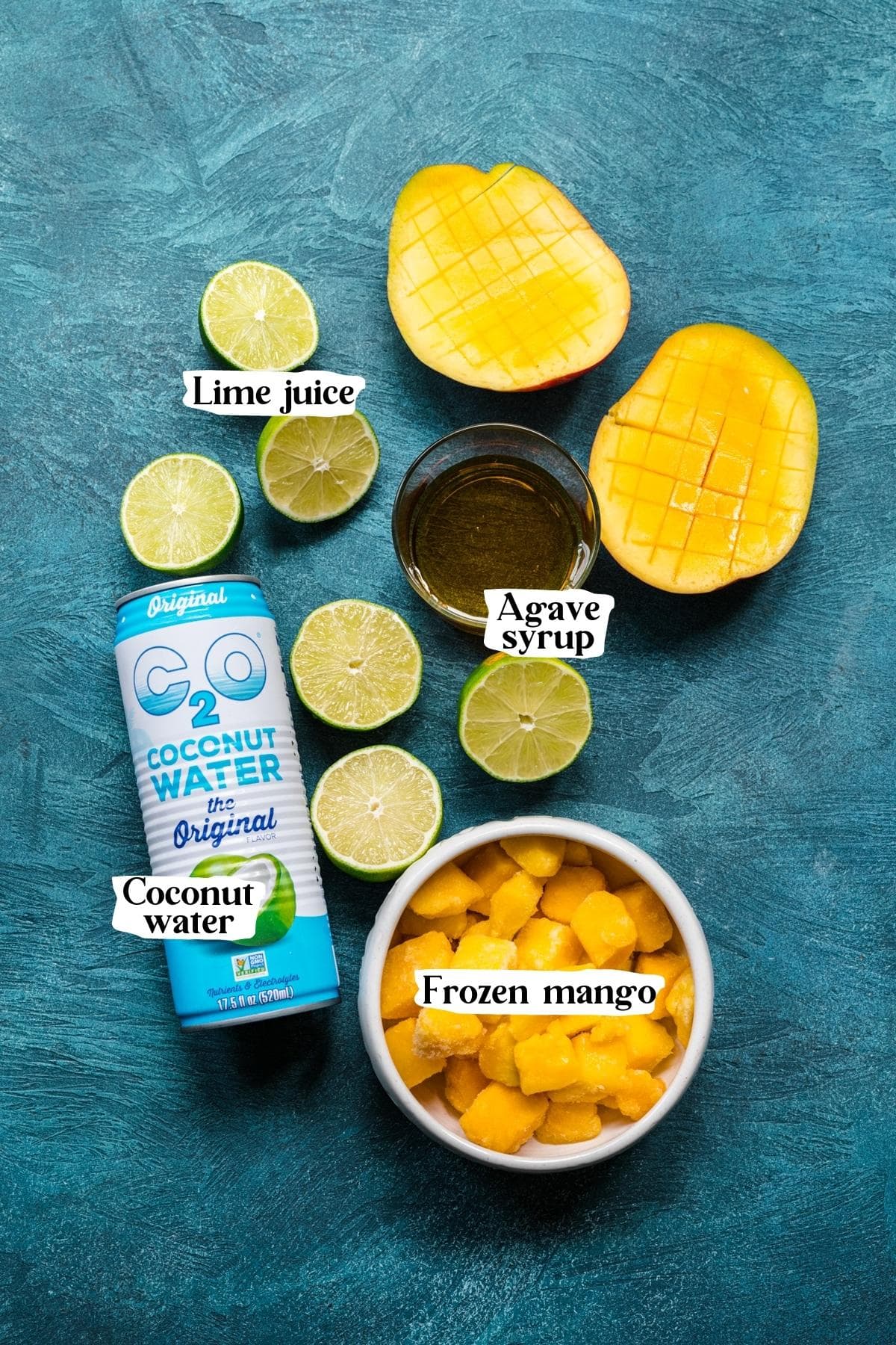 Overhead view of mango popsicle ingredients, including lime juice, frozen mango, agave syrup, and coconut water.