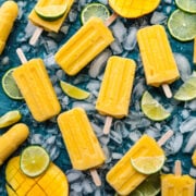 Overhead view of mango popsicles on a blue background.
