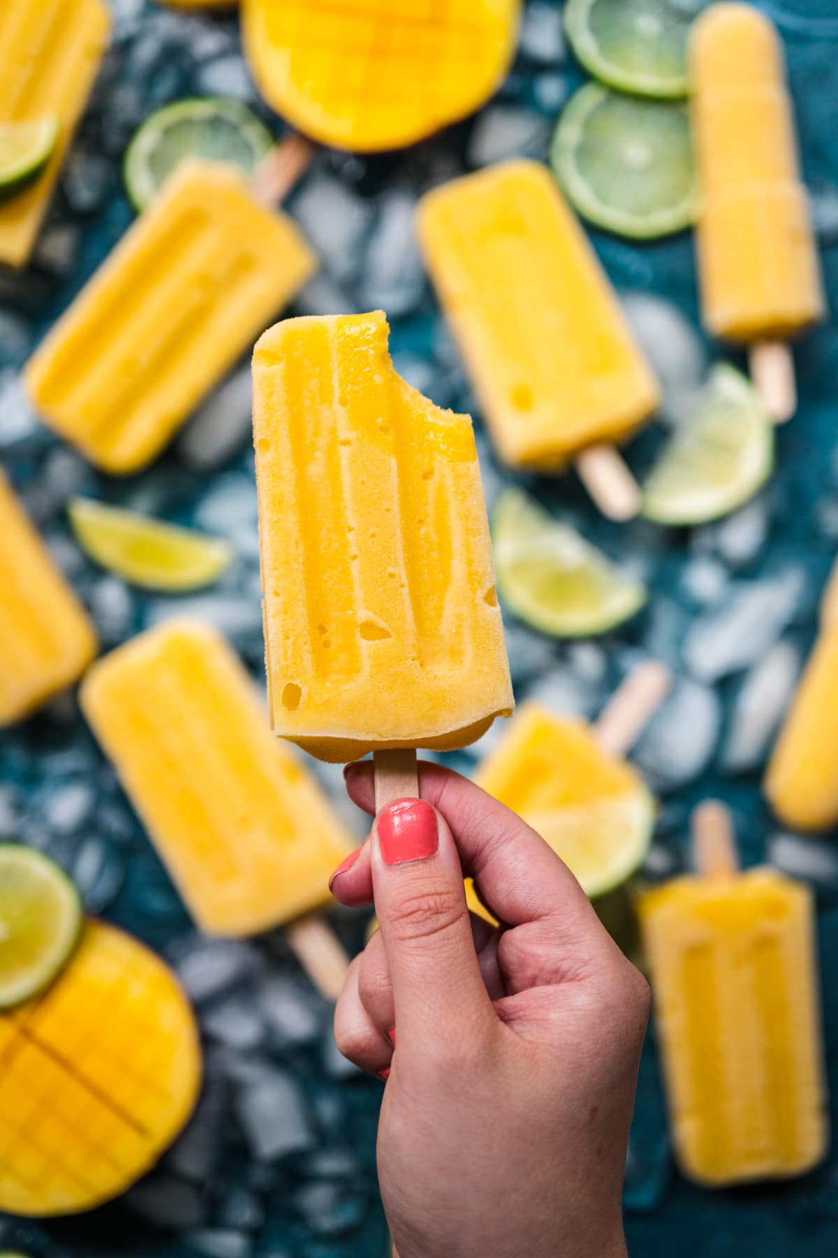 Close up view of mango popsicle with a bite taken out.