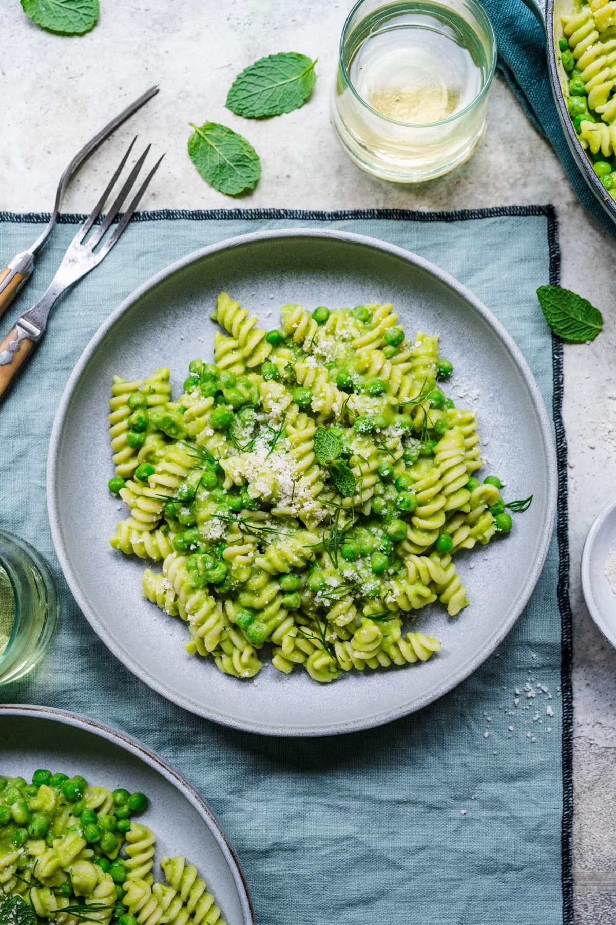 Overhead of finished pasta with pea sauce in bowl on green linen.