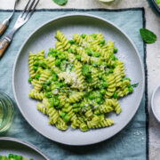 Overhead of finished pasta with pea sauce in bowl on green linen.