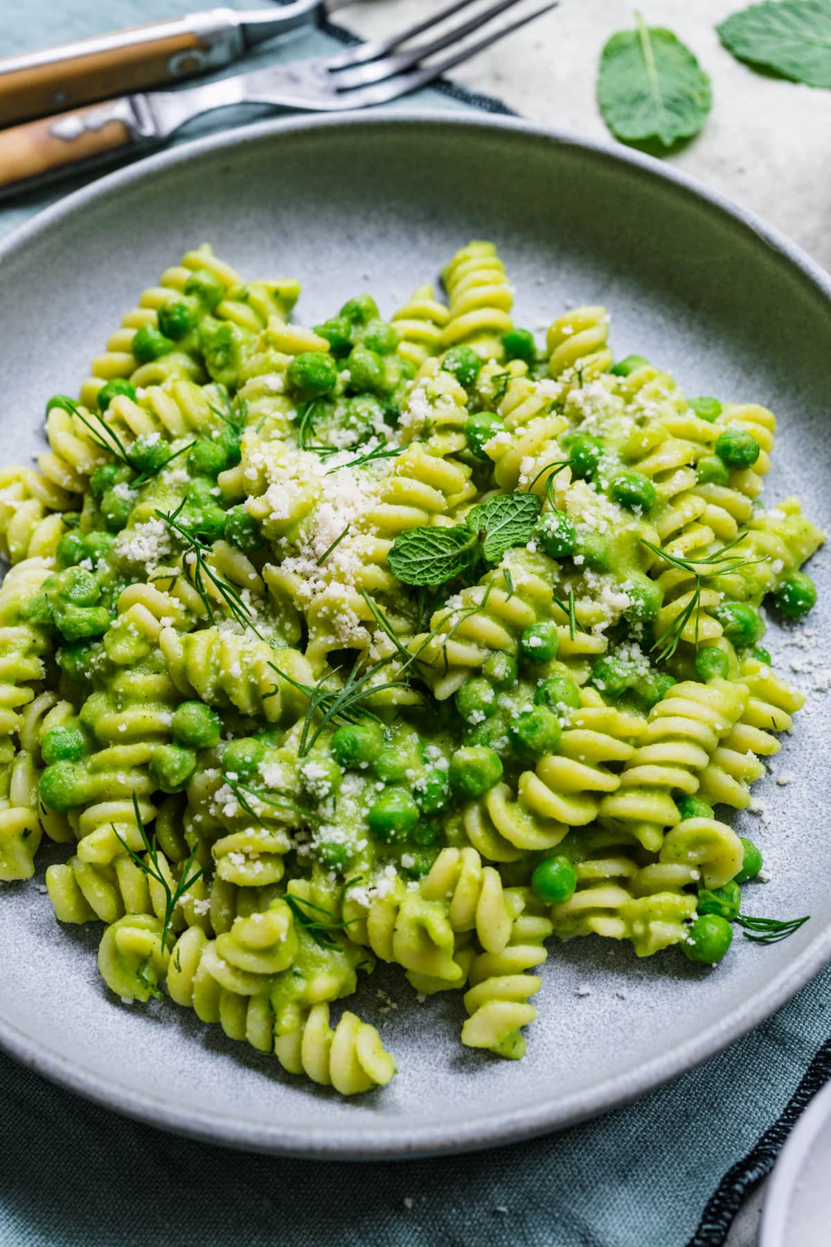 Close up on finished pasta with pea sauce in grey bowl.