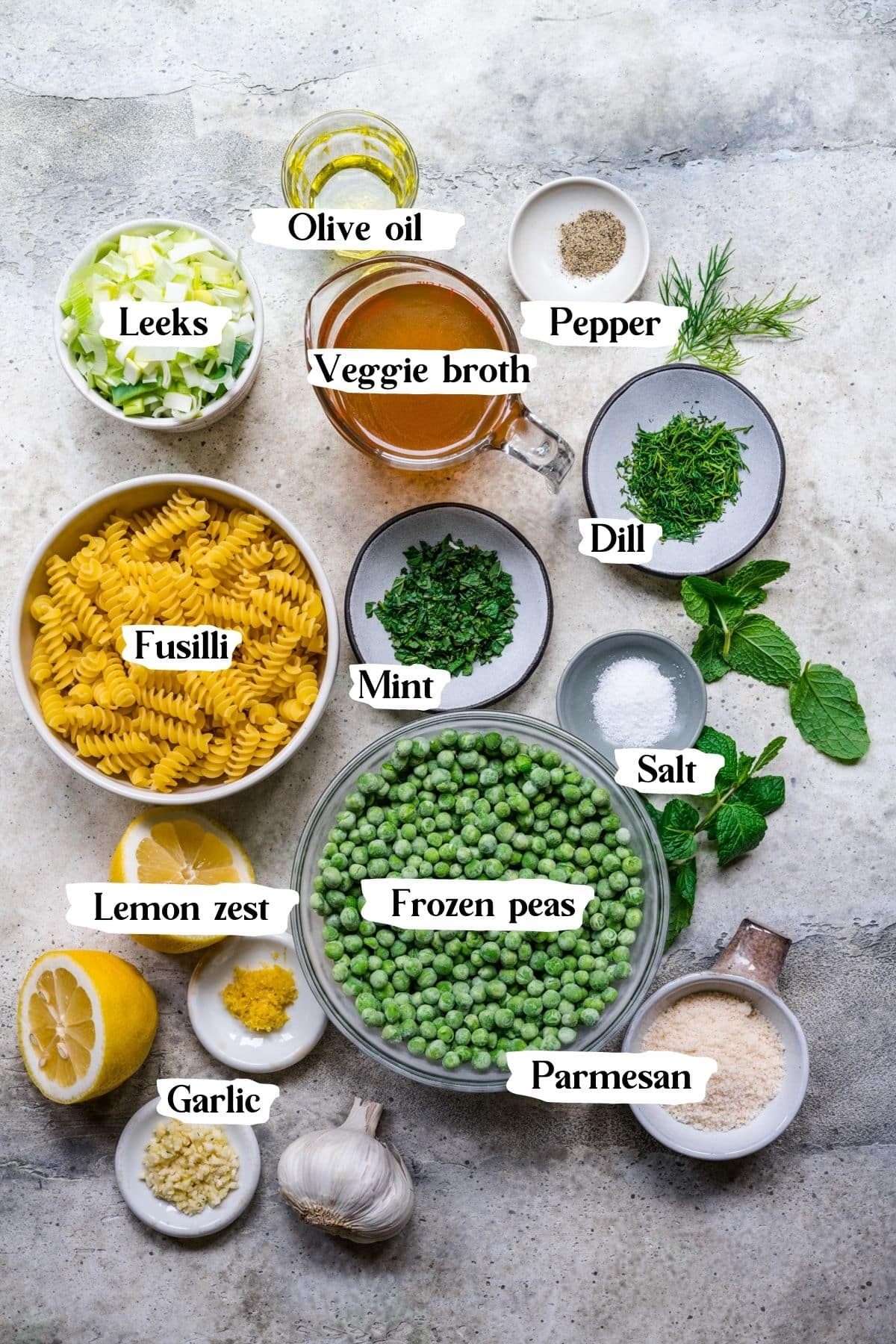 Overhead shot of pasta with pea sauce ingredients including fusilli, frozen peas and leeks.