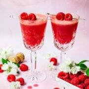 Front view of two raspberry mimosas garnished with raspberries.