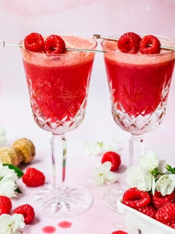 Front view of two raspberry mimosas garnished with raspberries.